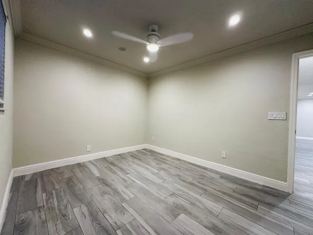 an empty room with wooden floor and fan