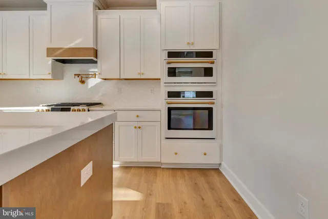 a kitchen that has a lot of cabinets in it and wooden floors