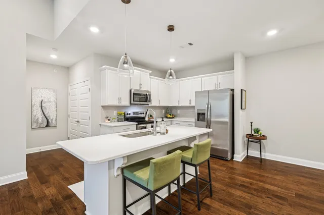 a kitchen with stainless steel appliances a dining table chairs and wooden floor