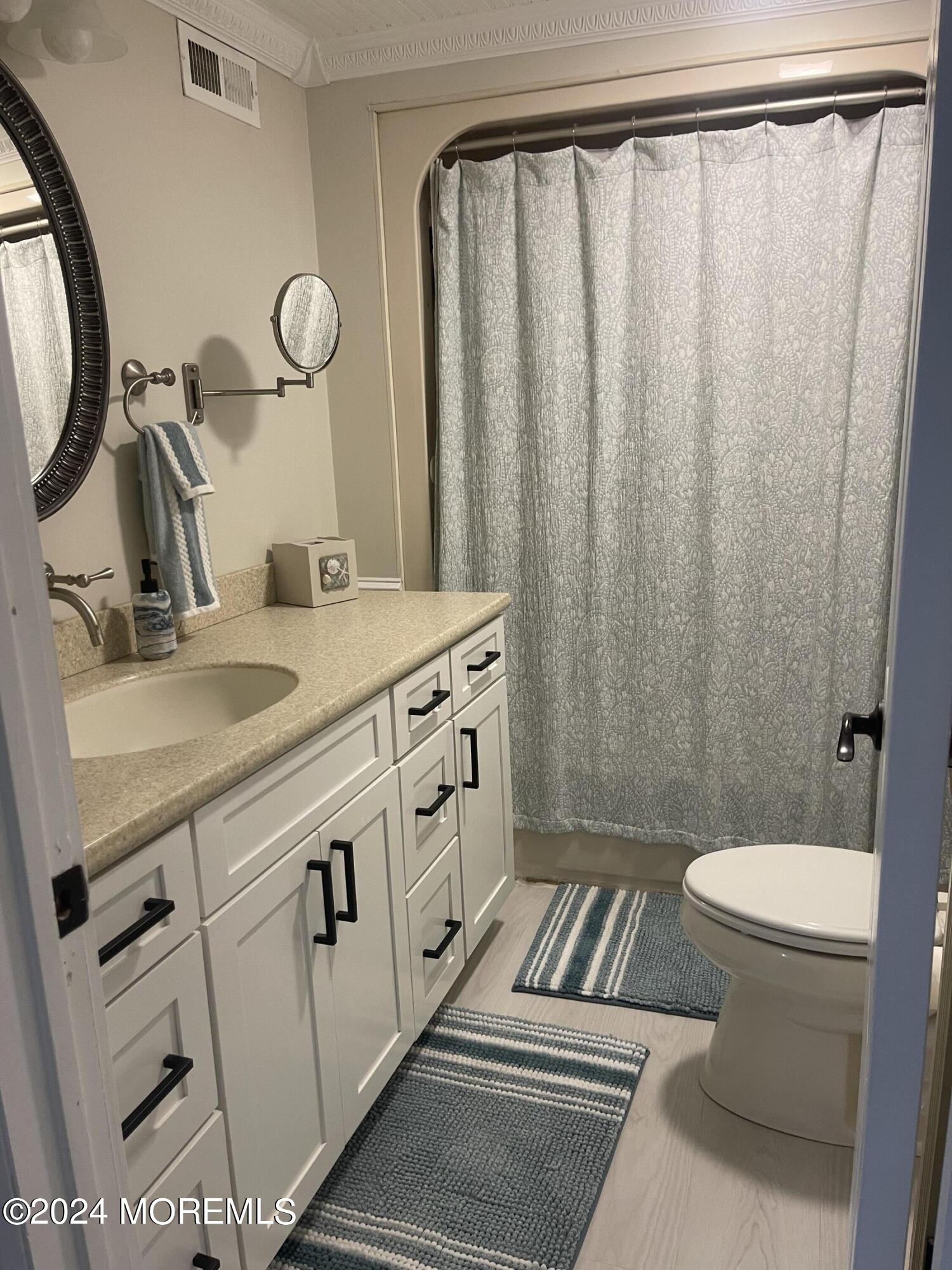 1407 River Road Belmar, NJ 07719 - Photo 22 of 26 a bathroom with a sink a toilet a mirror and shower curtain