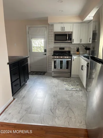 a kitchen with stainless steel appliances a stove a sink a microwave a refrigerator a counter top space and cabinets