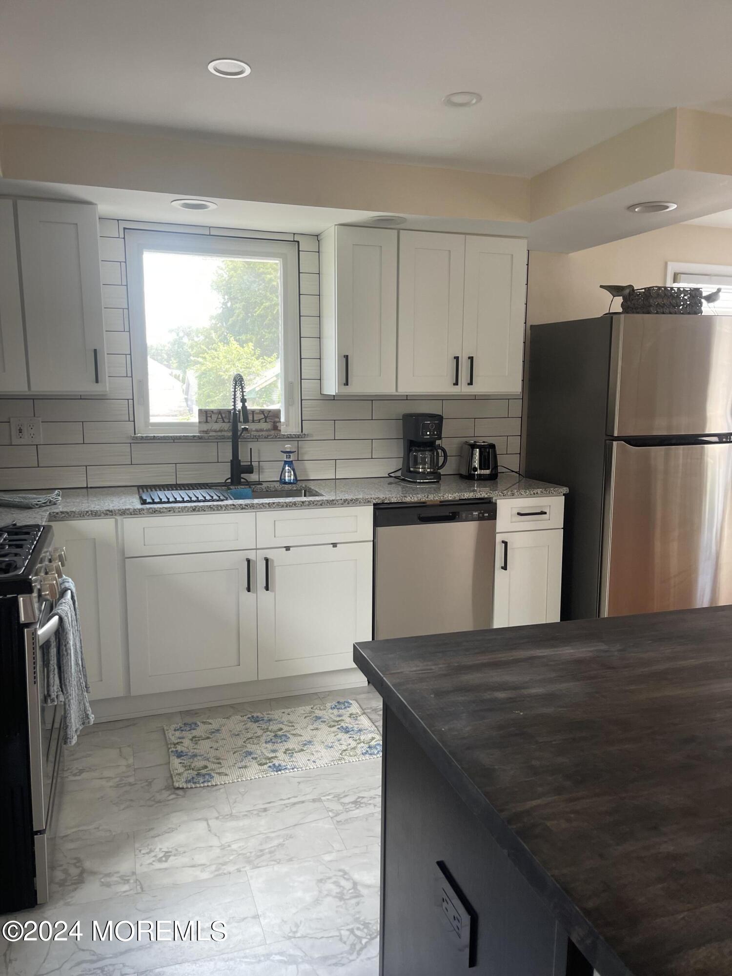 1407 River Road Belmar, NJ 07719 - Photo 5 of 26 a kitchen with a sink a stove a refrigerator a center island and a window