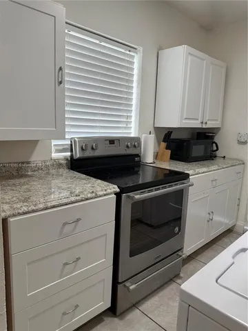 a kitchen with granite countertop white cabinets appliances and a sink