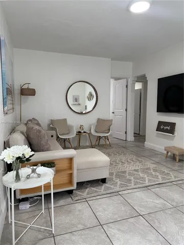 a living room with furniture a flat screen tv and a large window