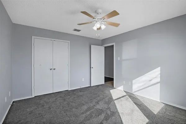 a view of an empty room with chandelier fan