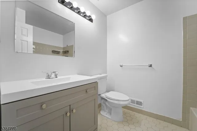 a bathroom with a granite countertop sink a toilet and a mirror