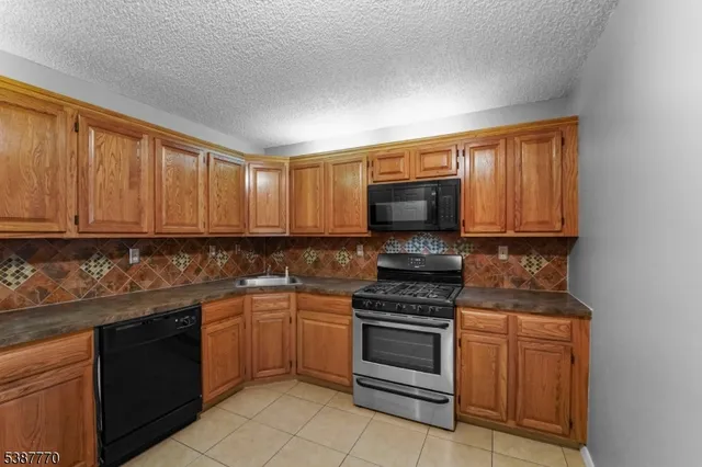a kitchen with granite countertop a stove top oven microwave and cabinets