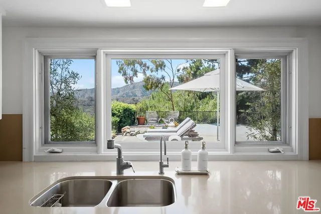 a kitchen with a large window and a view of living room