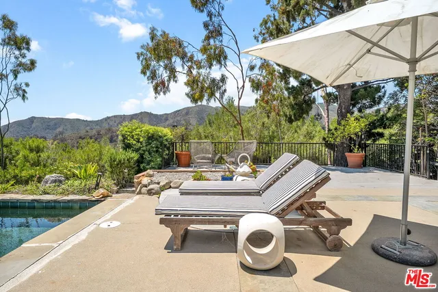 a view of a patio with couches table and chairs under an umbrella