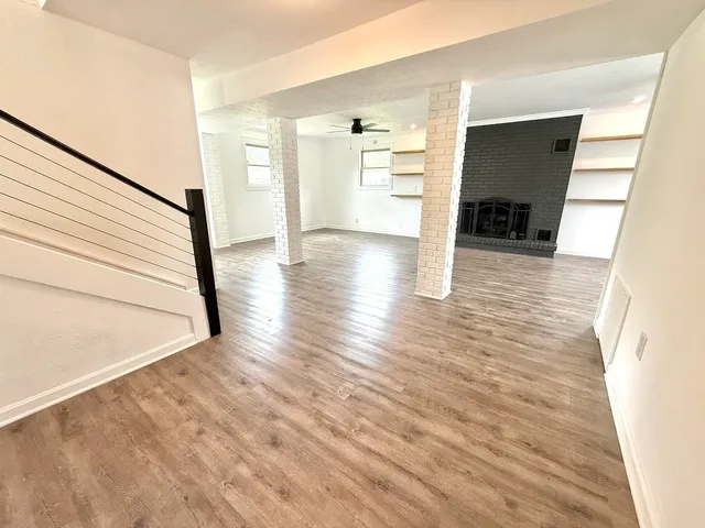 a view of empty room with wooden floor and fireplace