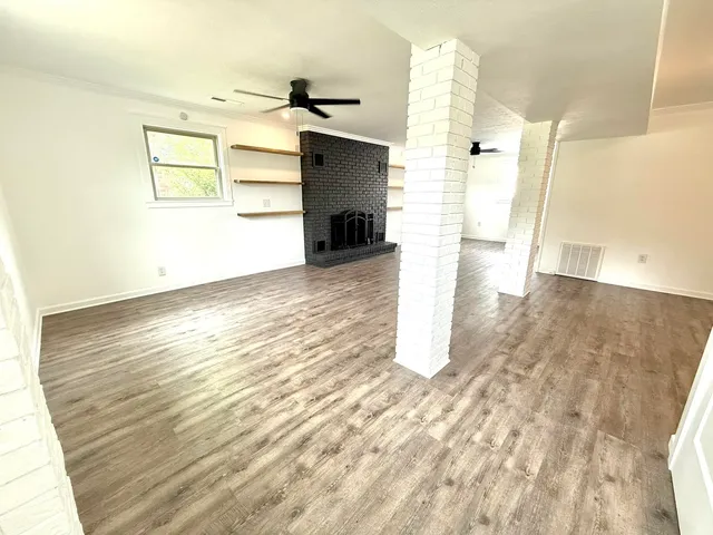 an empty room with wooden floor front door and windows
