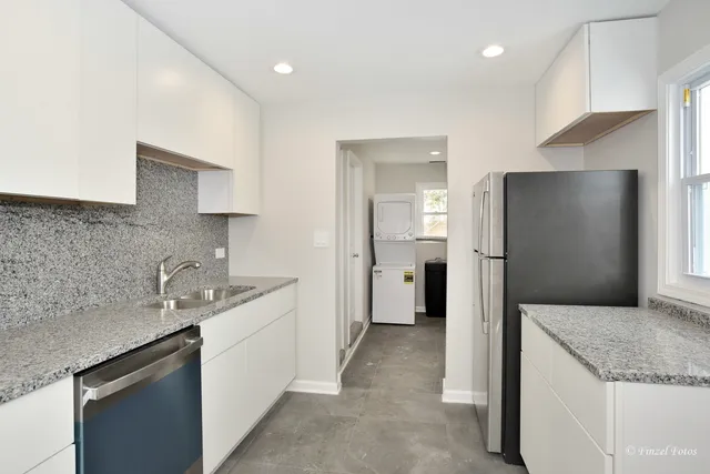 a kitchen with stainless steel appliances granite countertop a sink and a refrigerator