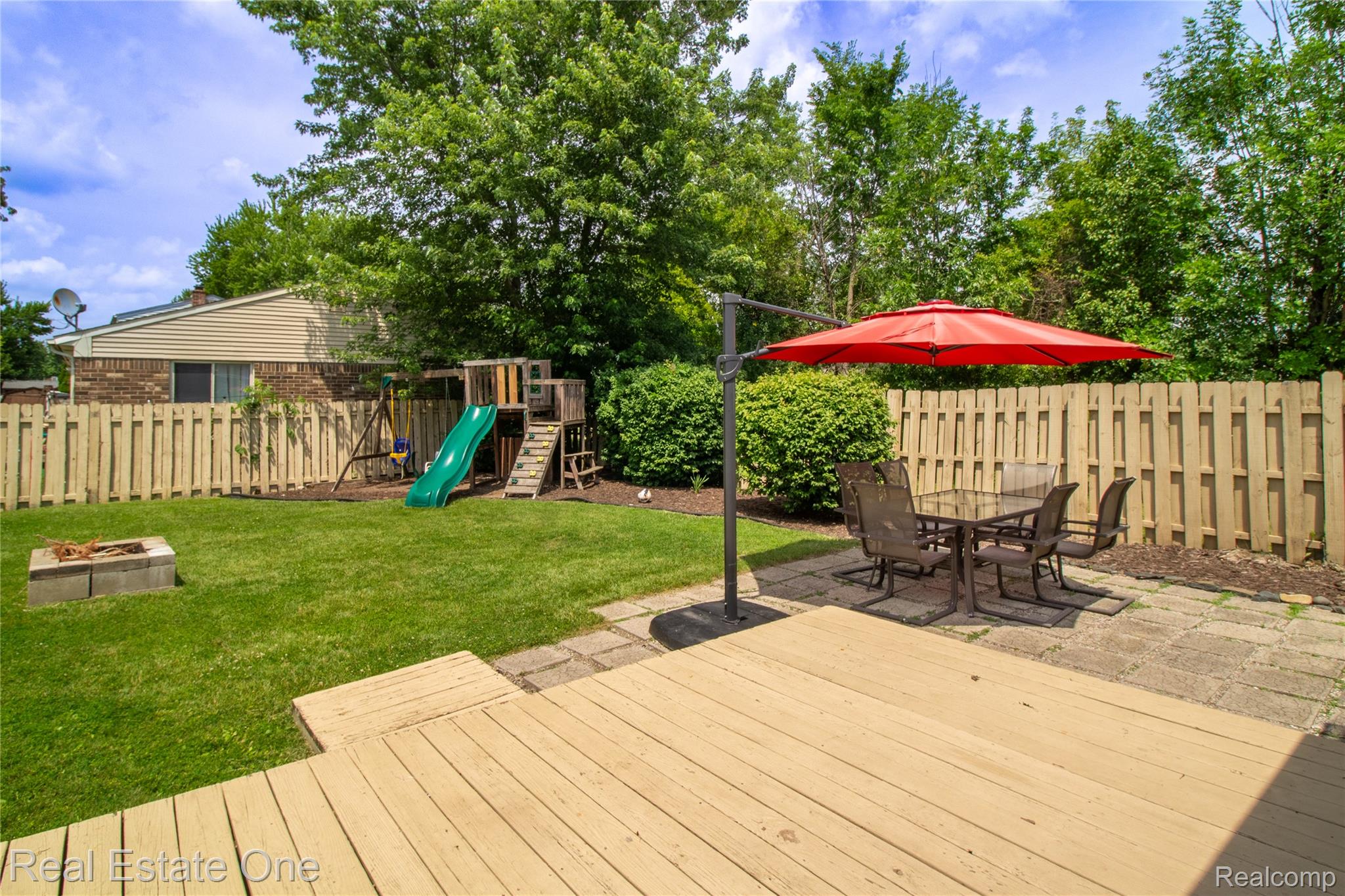 44220 Saltz Road Canton, MI 48187 - Photo 18 of 31 Expansive backyard featuring a wood deck, stone paver patio, full privacy fencing, and a built-in fire pit