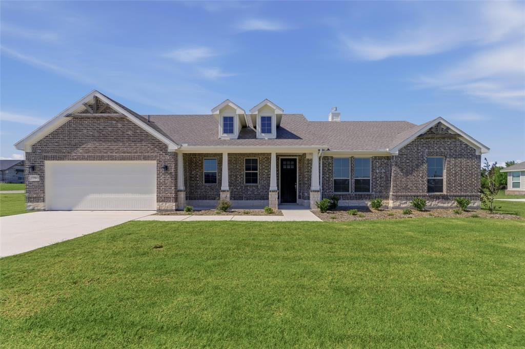 130 Fossil Canyon Drive Rhome, TX 76078 - Photo 3 of 25 Brick exterior with stone accents, a covered front porch, and a two-car garage