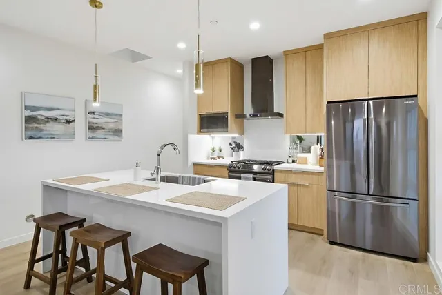 a kitchen with a sink a refrigerator a counter and chairs