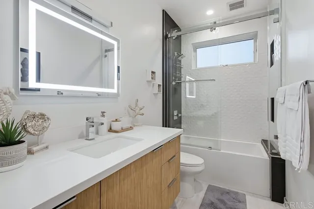 a bathroom with a granite countertop sink toilet and shower
