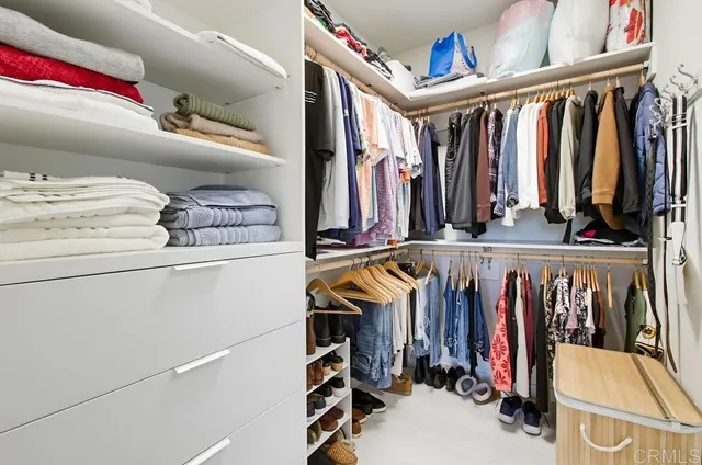 a view of walk in closet with clothes and shoes