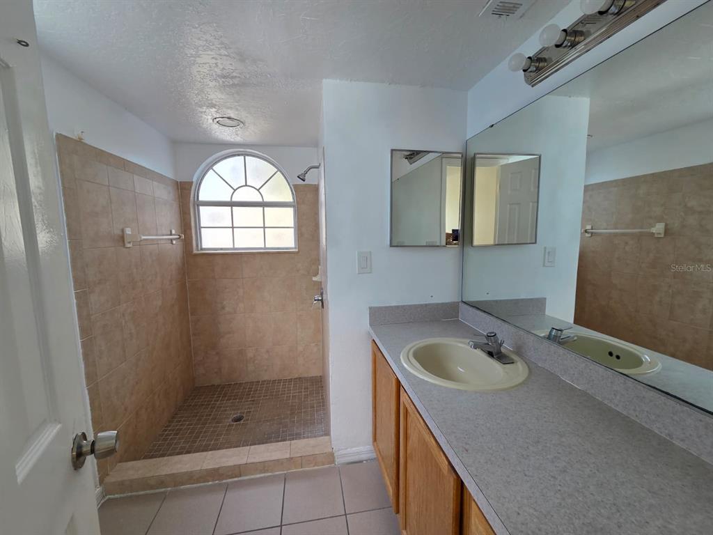 2751 North Poinciana Boulevard, Unit 27 Kissimmee, FL 34746 - Photo 11 of 18 a bathroom with a sink mirror and shower