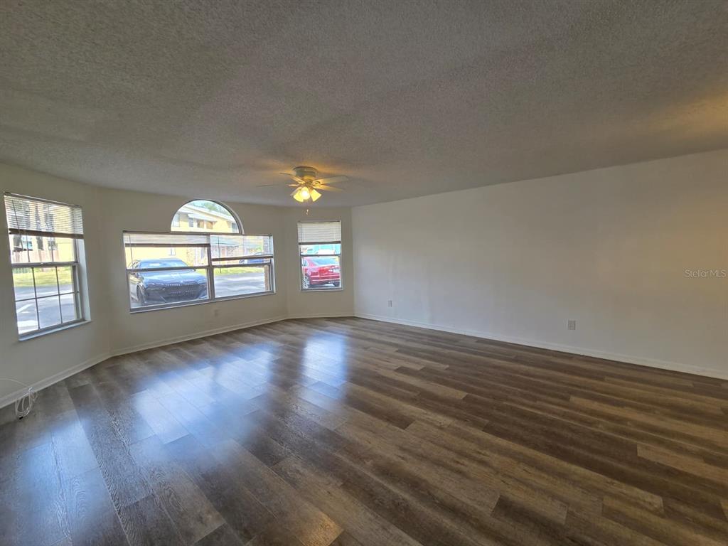 2751 North Poinciana Boulevard, Unit 27 Kissimmee, FL 34746 - Photo 4 of 18 an empty room with wooden floor and windows
