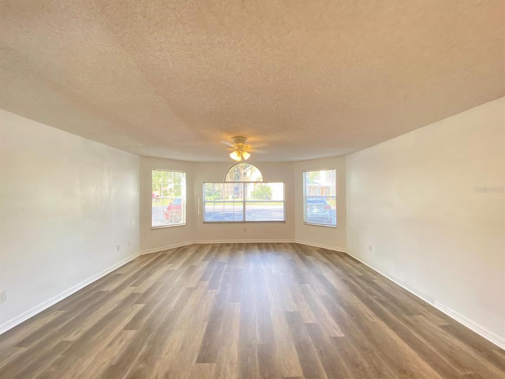 2751 North Poinciana Boulevard, Unit 27 Kissimmee, FL 34746 - Photo 5 of 18 an empty room with wooden floor and windows