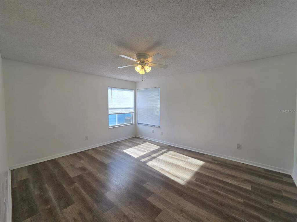 2751 North Poinciana Boulevard, Unit 27 Kissimmee, FL 34746 - Photo 9 of 18 an empty room with wooden floor and windows