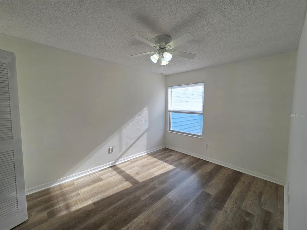 2751 North Poinciana Boulevard, Unit 27 Kissimmee, FL 34746 - Photo 10 of 18 an empty room with wooden floor fan and windows