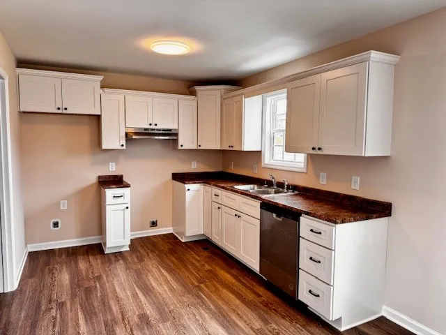 a kitchen with cabinets appliances wooden floor and a window