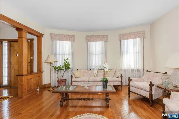 a living room with furniture large window and wooden floor
