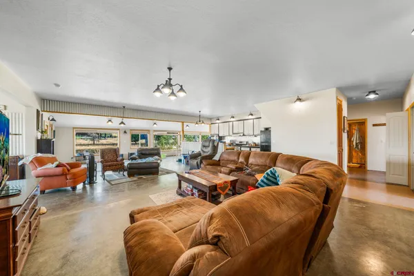 a living room with furniture kitchen view and a large window