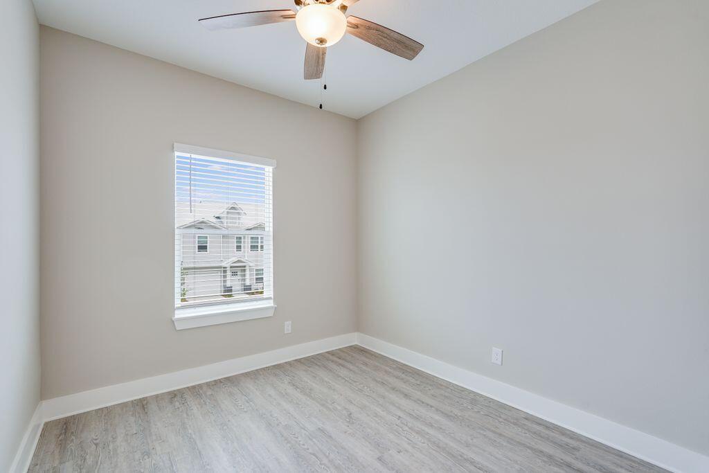 91 Date Palm Lane Freeport, FL 32439 - Photo 5 of 17 an empty room with wooden floor chandelier fan and windows
