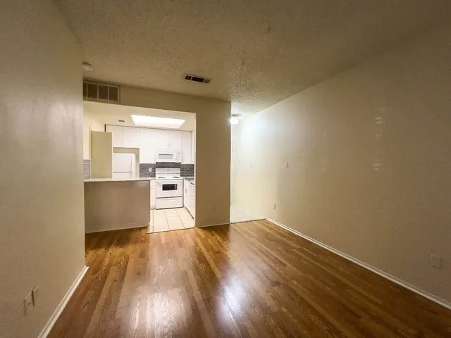 a view of a kitchen with wooden floor electronic appliances and stairs