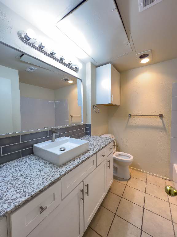 806 West 24th Street, Unit 130 Austin, TX 78705 - Photo 8 of 8 a bathroom with a granite countertop sink a toilet and a mirror