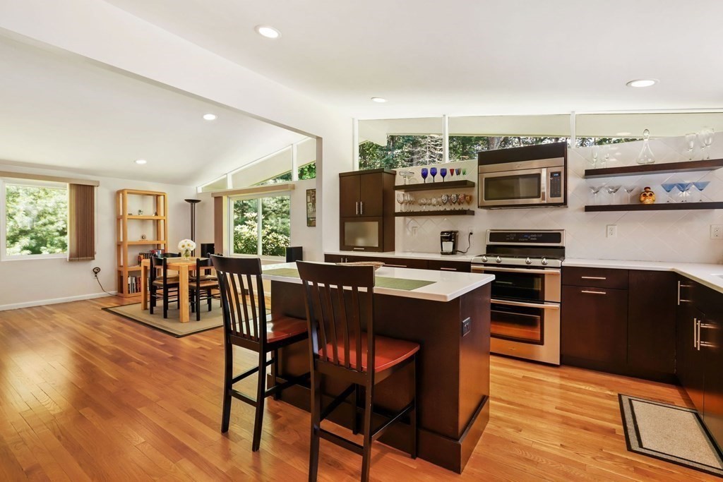 430 Heald Road Carlisle, MA 01741 - Photo 15 of 42 a kitchen with stainless steel appliances granite countertop a stove top oven a sink a dining table and chairs with wooden floor