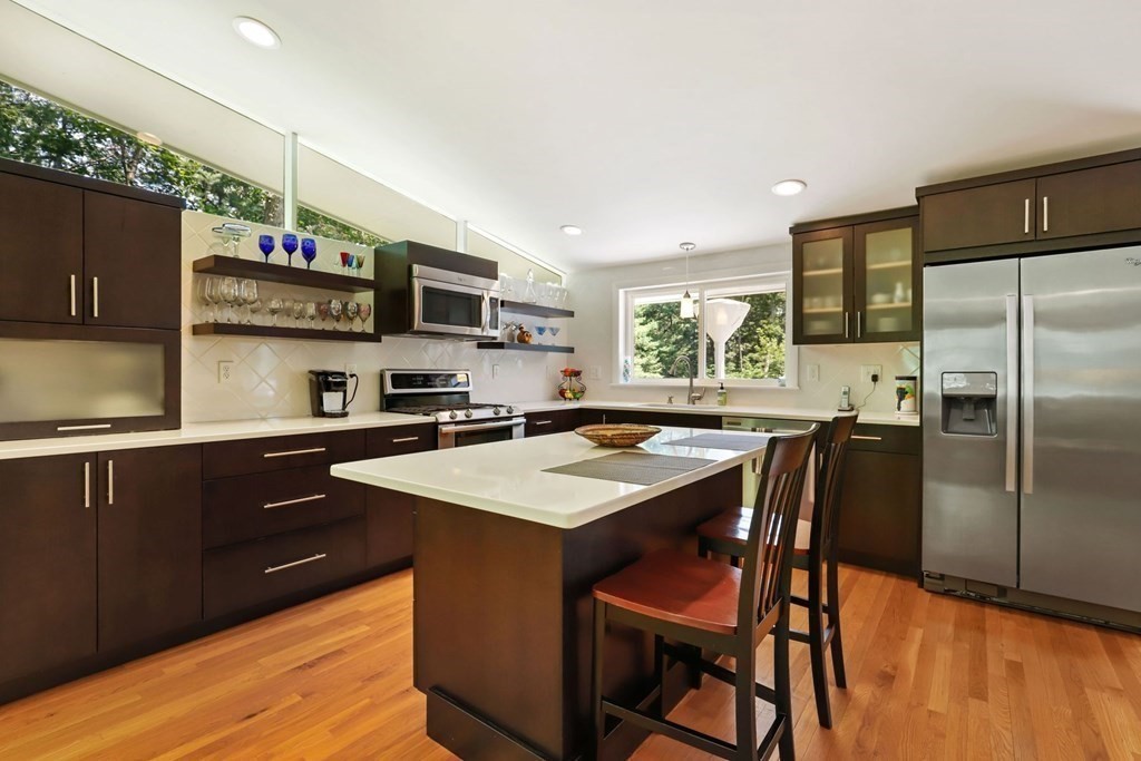 430 Heald Road Carlisle, MA 01741 - Photo 16 of 42 a kitchen with stainless steel appliances granite countertop a stove a refrigerator a sink a dining table and chairs with wooden floor
