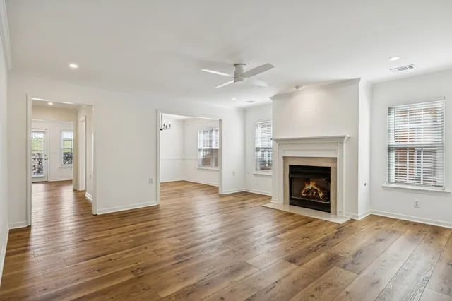 a view of an empty room with wooden floor fireplace and a window