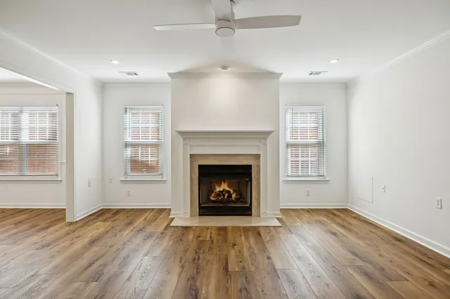 an empty room with wooden floor fireplace and windows