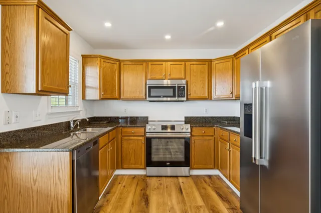 a kitchen with stainless steel appliances granite countertop a stove a sink and a refrigerator