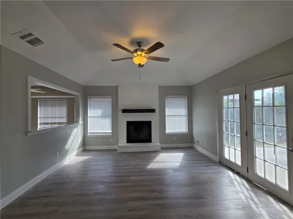 a view of a livingroom with a fireplace a ceiling fan and windows