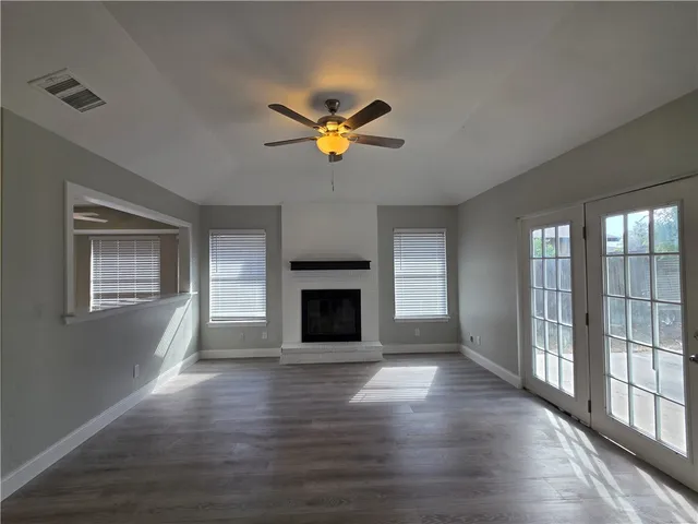 a view of a livingroom with a fireplace a ceiling fan and windows