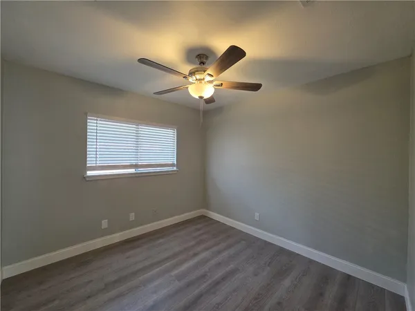 a view of an empty room with window and a ceiling fan