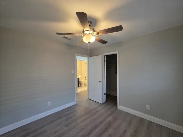 an empty room with closet and a chandelier fan