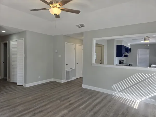 a view of a livingroom with a chandelier fan and wooden floor