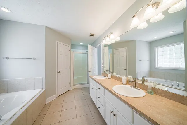 a spacious bathroom with a granite countertop double vanity sink a mirror and a bathtub