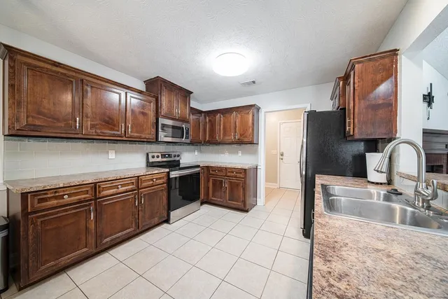 a kitchen with stainless steel appliances granite countertop a sink dishwasher stove and refrigerator