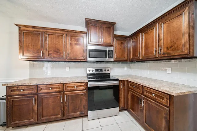 a kitchen with stainless steel appliances granite countertop wooden cabinets and a stove top oven