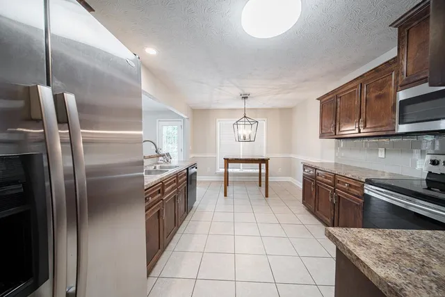 a kitchen with stainless steel appliances granite countertop a stove a sink and a refrigerator