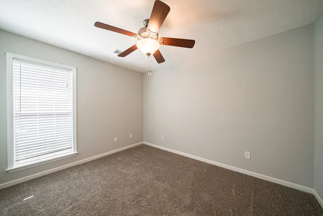 an empty room with windows and fan