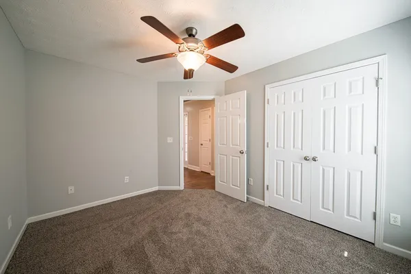 an empty room with closet and a ceiling fan