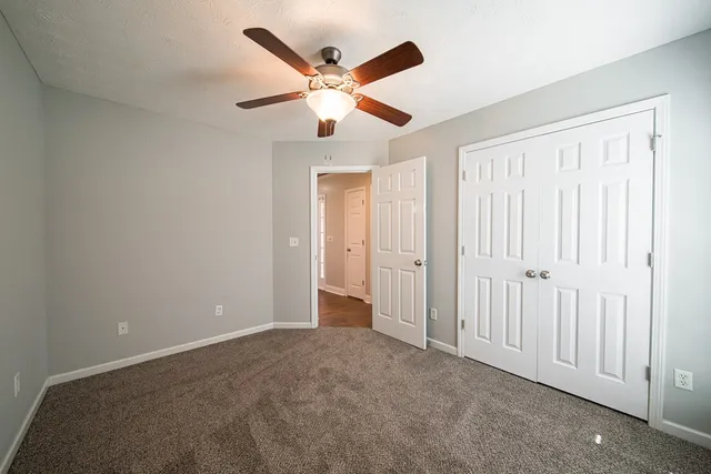 an empty room with closet and a ceiling fan