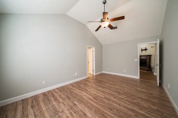 a view of an empty room with wooden floor and a ceiling fan